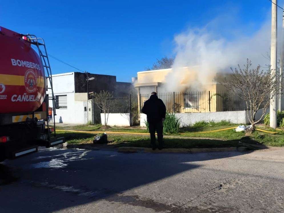 La casa incendiada, con los bomberos llegando para combatir las llamas.