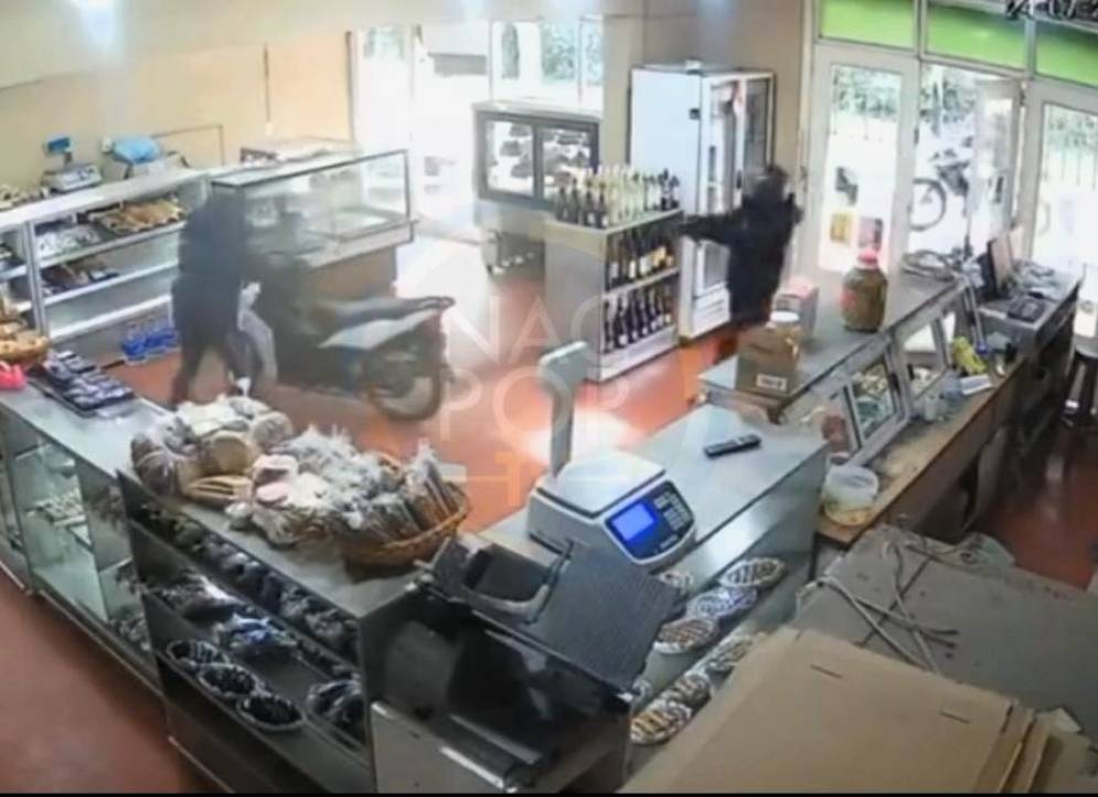 El ladr&oacute;n, con casco, apuntando a la v&iacute;ctima, dentro de la panader&iacute;a.